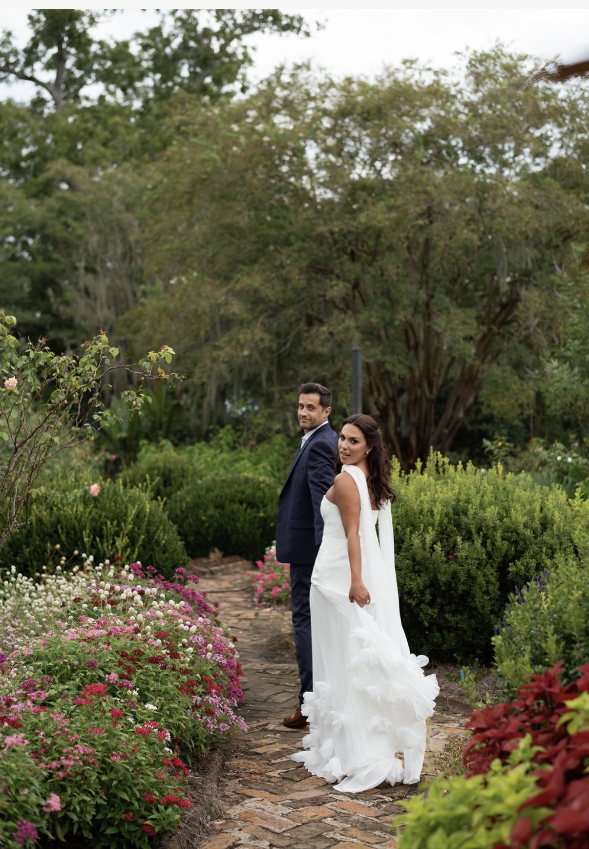 Chloe and Sam turning toward the camera on a flowering garden path