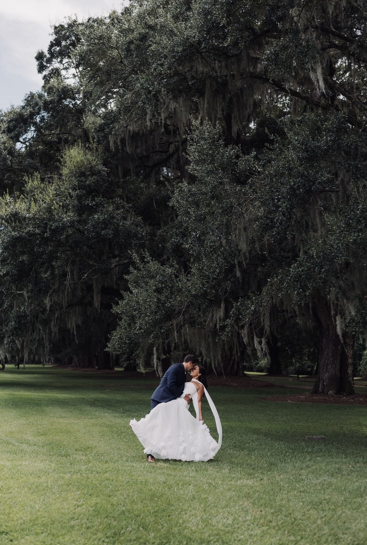 Sam dipping Chloe into a kiss beneath towering Charleston oaks and Spanish moss